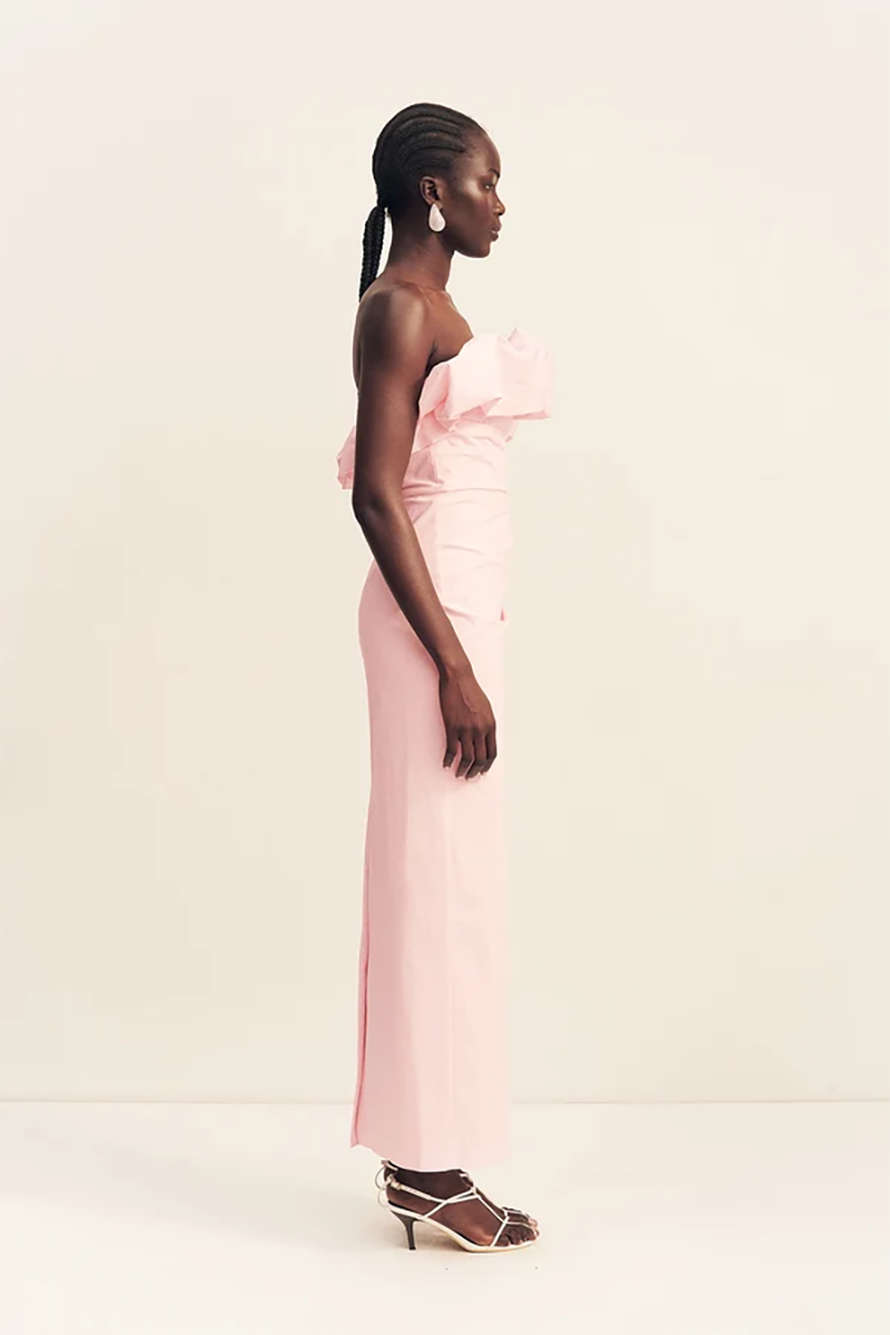 A woman in profile wearing the ballerina pink Shona Joy Campbell Strapless Bubble Maxi Dress with a ruffled bodice and heeled sandals.