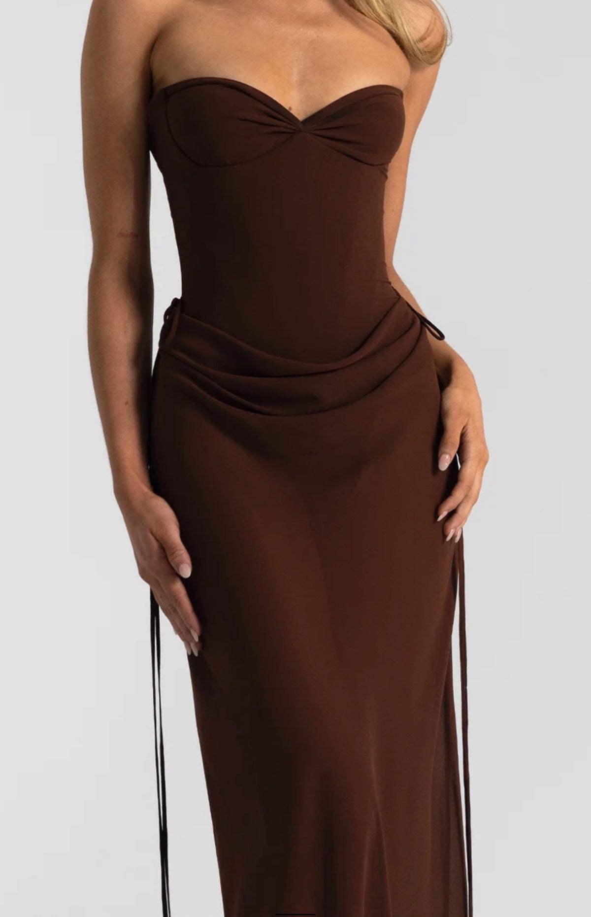 A person wears the chocolate Verity & Allira Set, a midi dress featuring a strapless sweetheart neckline and a draped, gathered waist detail.