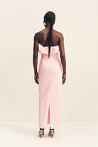 Back view of a person wearing a ballerina pink Shona Joy Campbell Strapless Bubble Maxi Dress with a floor-length hem, a back slit, and strappy heels.